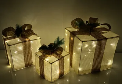 Three illuminated gift boxes are arranged on a surface.