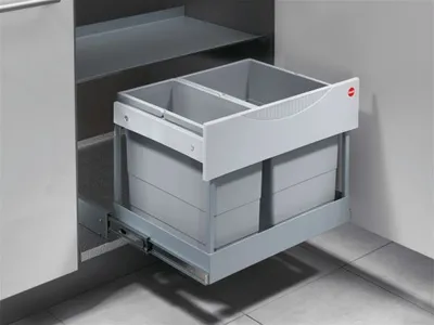 A pull-out trash bin with two compartments inside a cabinet.