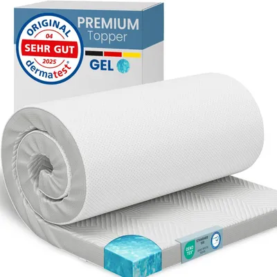 A rolled-up mattress topper is shown on a surface, with its packaging in the background.