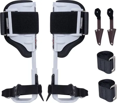 A pair of white and black tree climbing spikes with straps and two brown leather sheaths, arranged on a white background.
