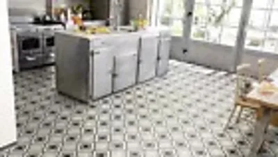 A kitchen with a patterned floor, a stainless steel island, and a stove.