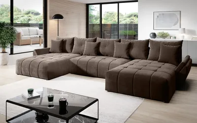 A large, U-shaped sectional sofa in a modern living room with large windows overlooking an outdoor patio.