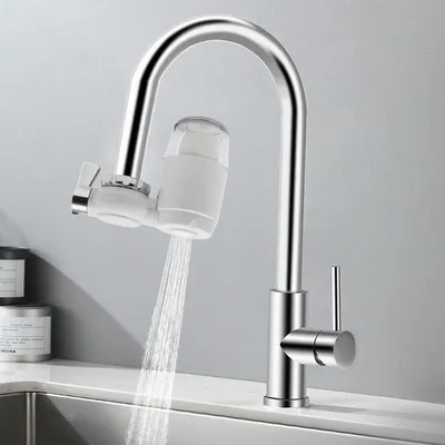 A chrome kitchen faucet with a white water filter attached, dispensing water into a sink.