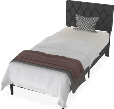 A studio shot of a single bed with bedding and a pillow.