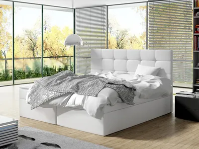A modern bedroom with a large window overlooking trees in autumn. The bed is the main focus.