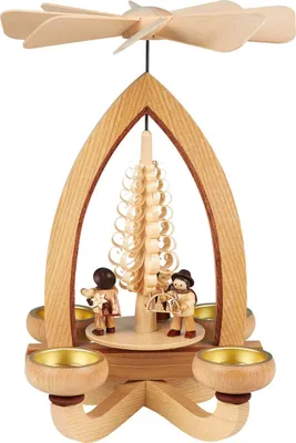 Eine kunstvoll gestaltete Teelichtpyramide aus Holz zeigt zwei Figuren und einen Baum in der Mitte während oben ein Flügelrad angebracht ist das sich durch die Wärme der Teelichter dreht und eine warme Atmosphäre schafft