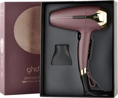A burgundy GHD Helios hairdryer is presented in its black packaging, alongside its box which features a gold circular pattern and the GHD logo.