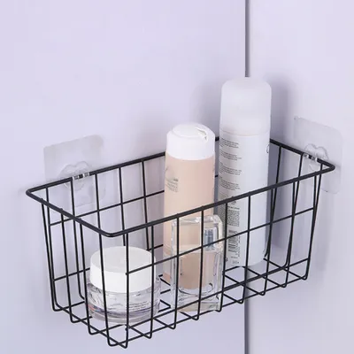 A black wire basket shelf mounted on a white wall, holding several toiletries.