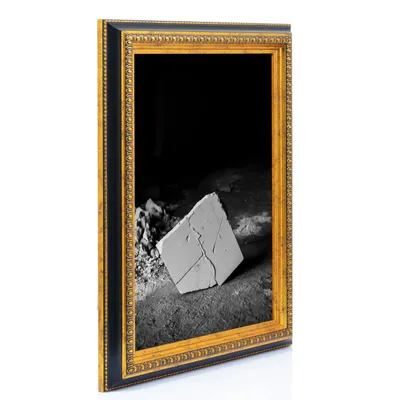 A framed picture of a broken piece of plaster on the ground.