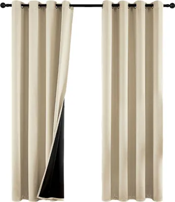 Two beige curtains hanging from a curtain rod, with one curtain pulled back to reveal a black lining.