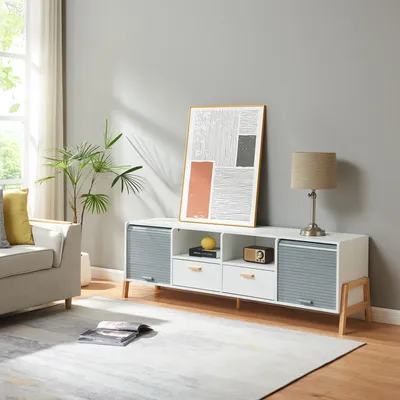 A modern living room scene featuring a white and gray media console with wooden legs, decorated with a framed abstract art piece and a table lamp.