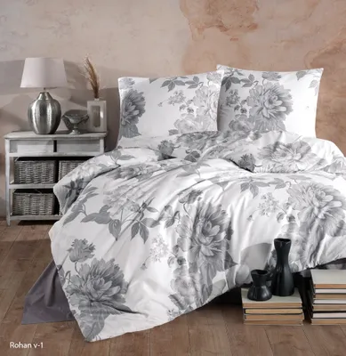 A neatly made bed with a floral duvet and pillows, next to a bedside table with a lamp and baskets.