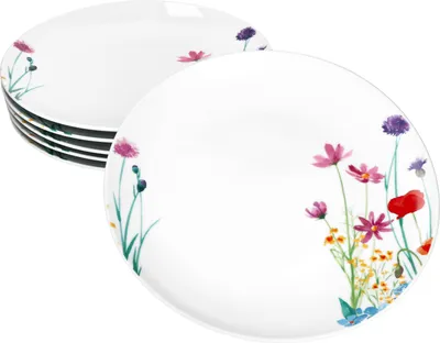 A stack of white plates with a floral design on the edges, with one plate in the foreground.