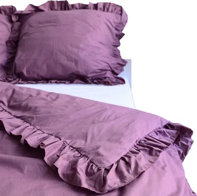 A close-up view of a purple duvet cover and pillowcase with ruffled edges, laid out on a bed.
