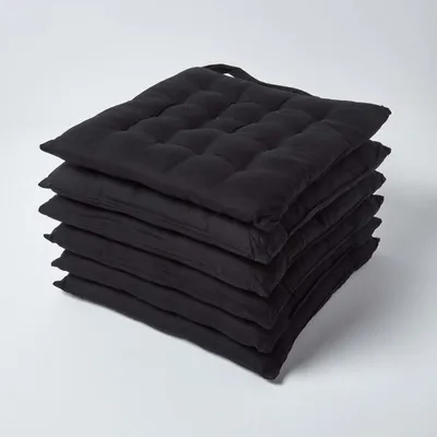 A stack of black seat cushions on a white background.