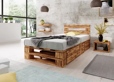 A bedroom with a wooden pallet bed, nightstand, and large window.