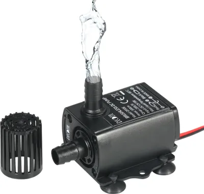 A small black submersible water pump with water spraying from its outlet, shown with a separate filter attachment.
