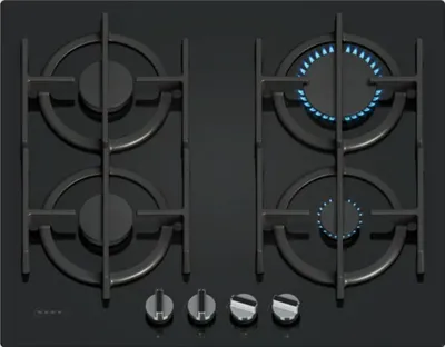 A top-down view of a black gas hob with four burners, two of which are lit.