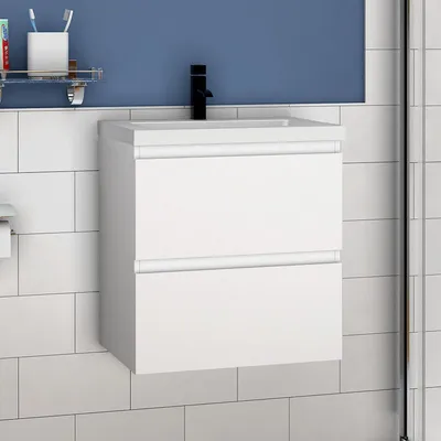 A white bathroom vanity with two drawers is mounted on a tiled wall.