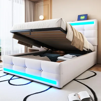 A white upholstered bed with storage is shown with the mattress lifted, revealing stored items. Blue LED lights illuminate the base of the bed.