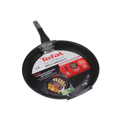 A black Tefal frying pan with product information labels attached.