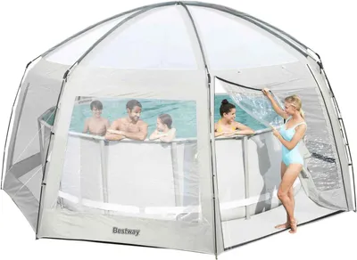 A family is enjoying themselves in an above-ground swimming pool covered by a large, transparent tent.