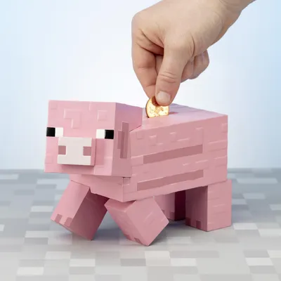 A hand is inserting a coin into a pink Minecraft pig piggy bank.