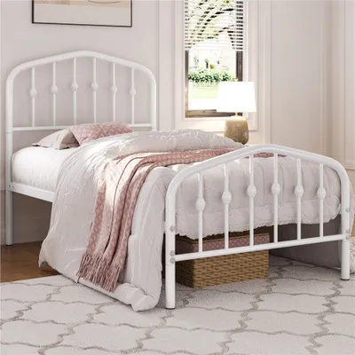 A white metal bed frame with bedding in a bedroom setting.