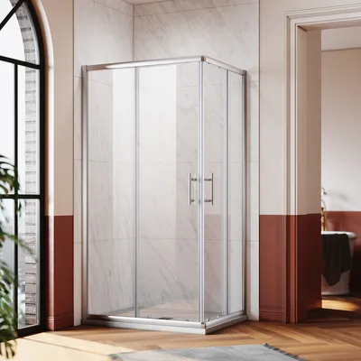 A modern bathroom with a glass shower enclosure, marble-tiled walls, and wooden flooring.