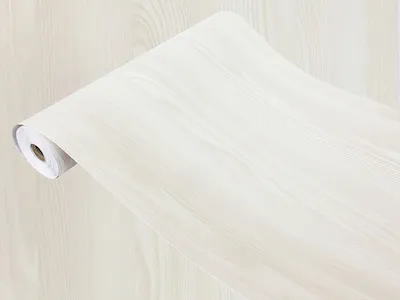 A roll of wallpaper with a light wood grain pattern, lying on a surface with a matching pattern.
