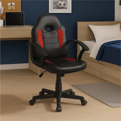 A gaming chair is placed in a bedroom setting next to a bed and a desk.