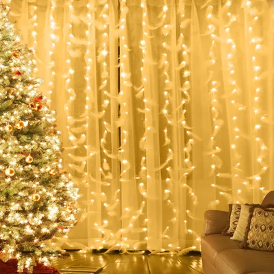 A decorated Christmas tree and a curtain with lights and feathers.