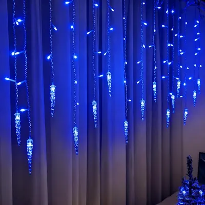 Blue icicle-shaped LED lights hanging in front of a curtain.