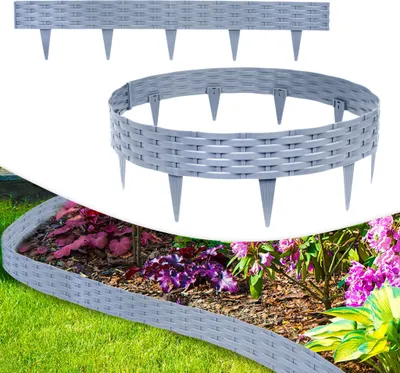 A garden border made of gray plastic in a rattan look is shown installed around a flower bed with green grass in the foreground.
