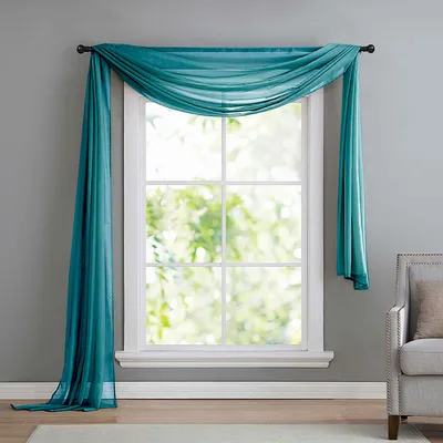 A teal sheer scarf draped over a window.