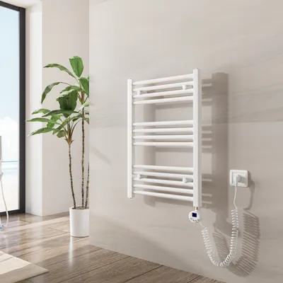 A white electric towel warmer mounted on a light gray tiled wall in a modern bathroom.