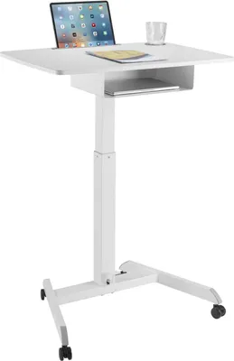 A white adjustable height standing desk with a laptop, a book, and a glass of water on it.