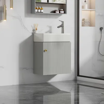 A minimalist bathroom vanity with a white sink and a gray cabinet, set against a marble-tiled wall.