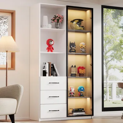 A tall, white bookshelf with a glass-fronted cabinet section, displaying various collectible figures and books. The scene is set in a well-lit room with a window and a lamp visible.