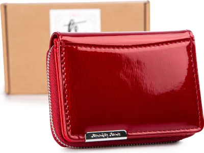 A red patent leather wallet is displayed in front of a cardboard box.
