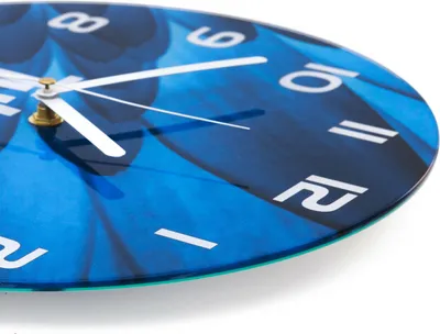 A close-up, angled view of a round glass clock with a blue marble texture background and white hands and numbers.