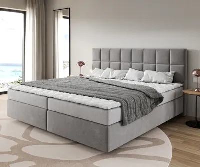 A modern bedroom with a large bed, large windows with a view of the ocean, and subtle interior design elements.