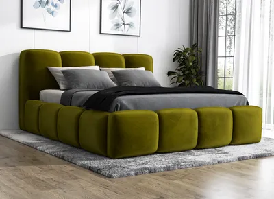 A green upholstered bed with a headboard and footboard, set up in a bedroom with artwork on the wall and curtains in the background.