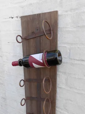 A wooden wine rack with iron accents mounted on a brick wall.