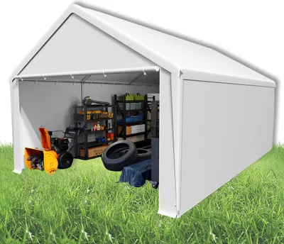A white storage tent with various items inside, including a snowblower, shelves with supplies, and tires, set on a grassy lawn.