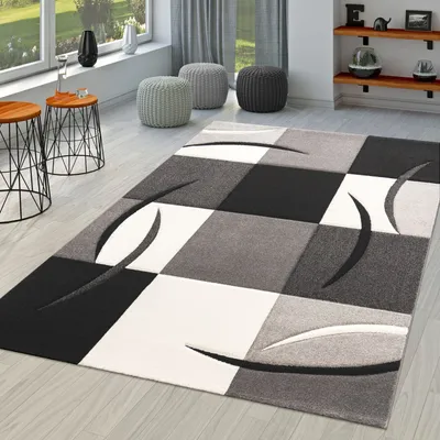 A modern living room with a geometric rug, side tables, and poufs.