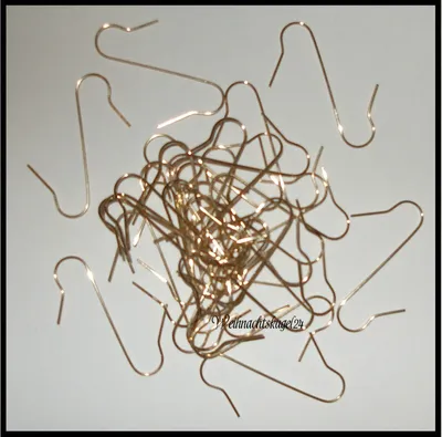 A pile of gold-colored metal ornament hooks scattered on a light gray surface.