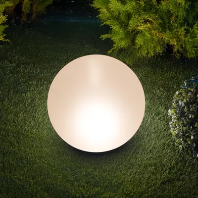 A glowing sphere sits on artificial grass, surrounded by greenery.