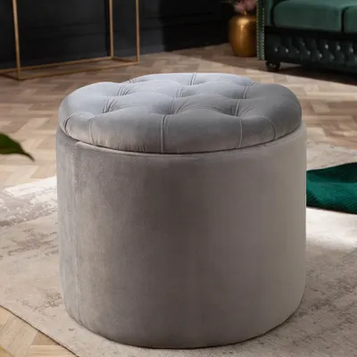 A tufted ottoman sits on a rug in a room.
