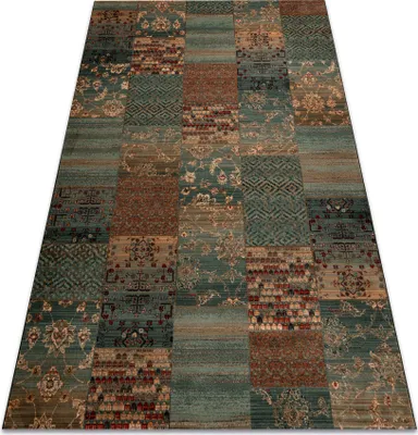 A patchwork rug with green, brown, and blue tones is shown from a diagonal angle.